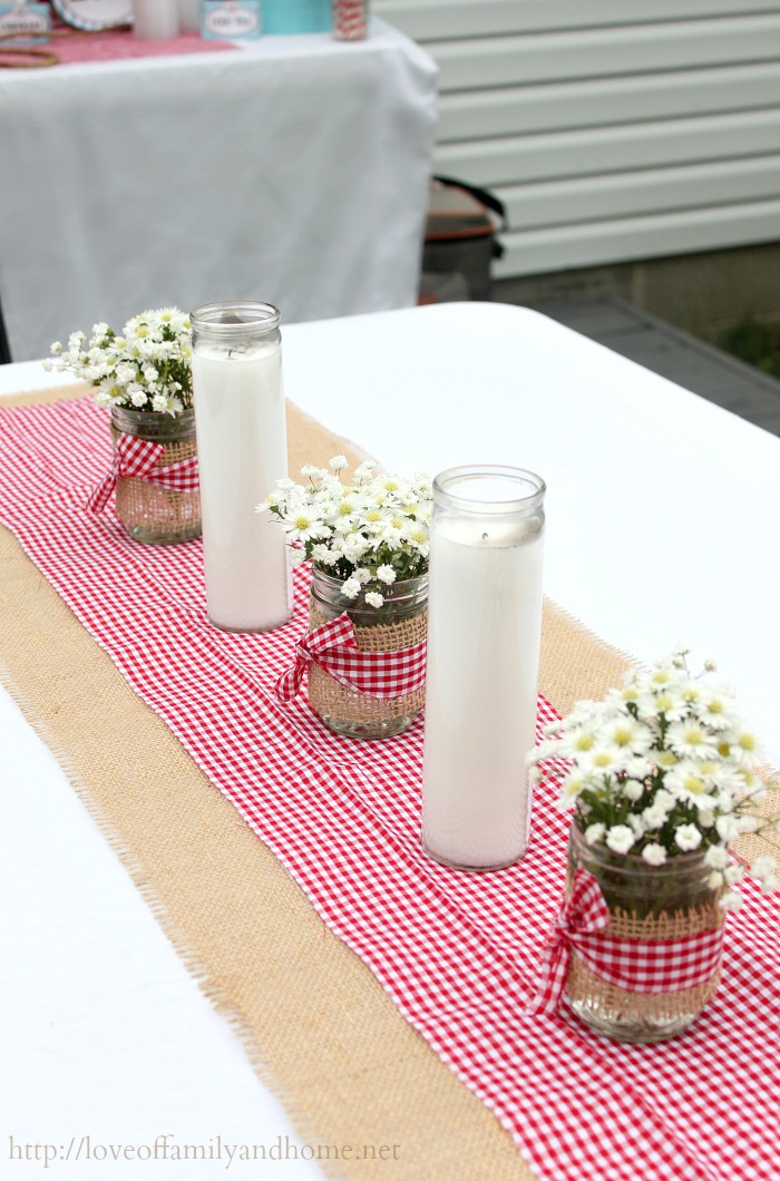 Inexpensive jar candles from the dollar tree & mason jars wrapped in burlap with red gingham bow. Simple & easy table decor for western/cowboy themed party.